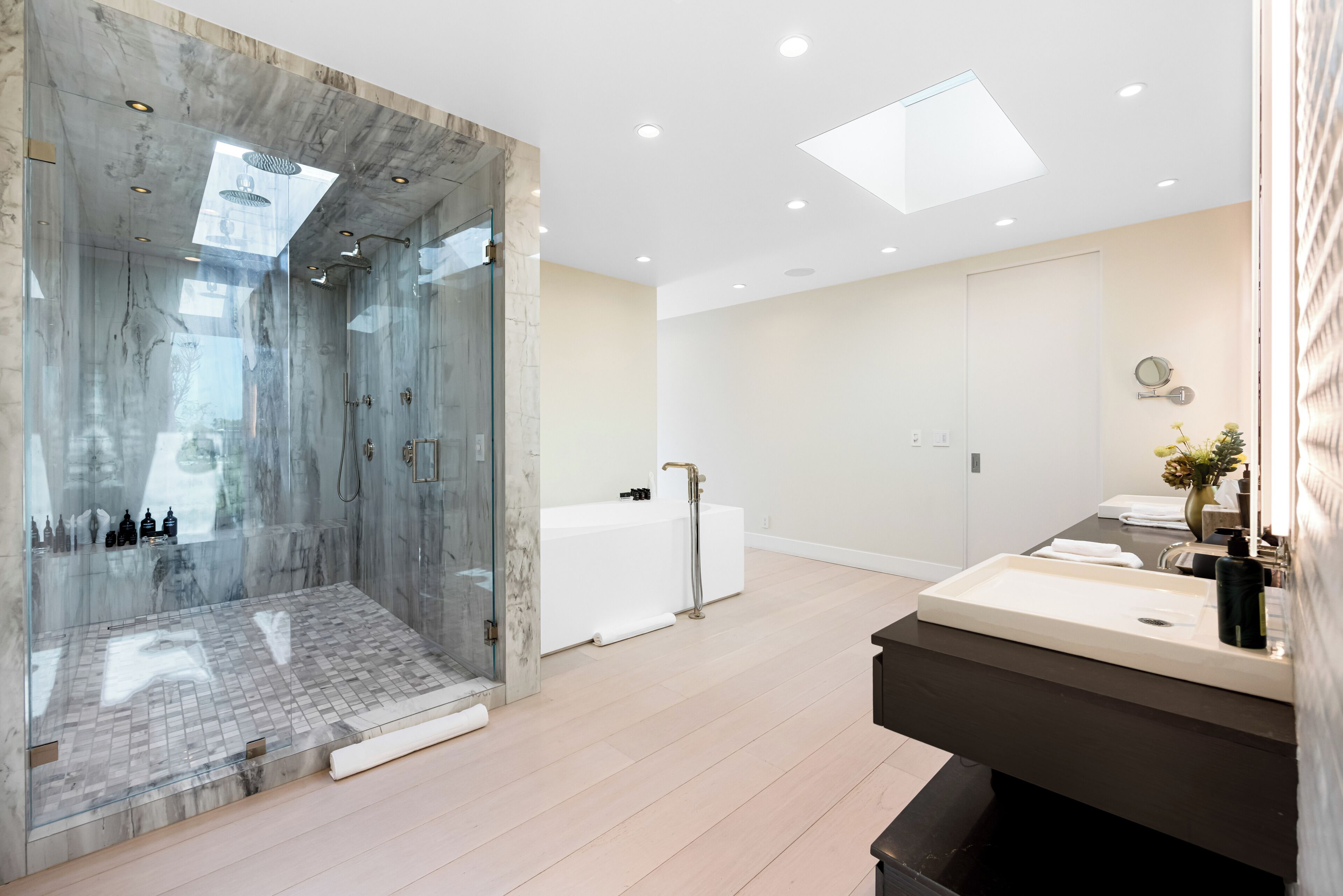 A modern bathroom with a glass-enclosed shower, a large mirror, and a vanity with a sink.