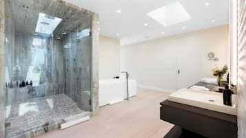 A modern bathroom with a glass-enclosed shower, a large mirror, and a vanity with a sink.
