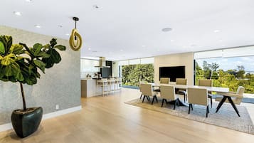 A modern kitchen with a dining area, large windows, and a potted plant.