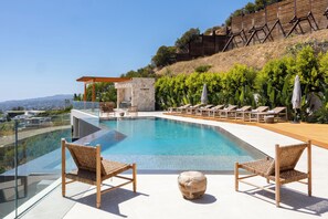 Una piscina con sillones de descanso, una construcción de piedra y vistas al paisaje.
