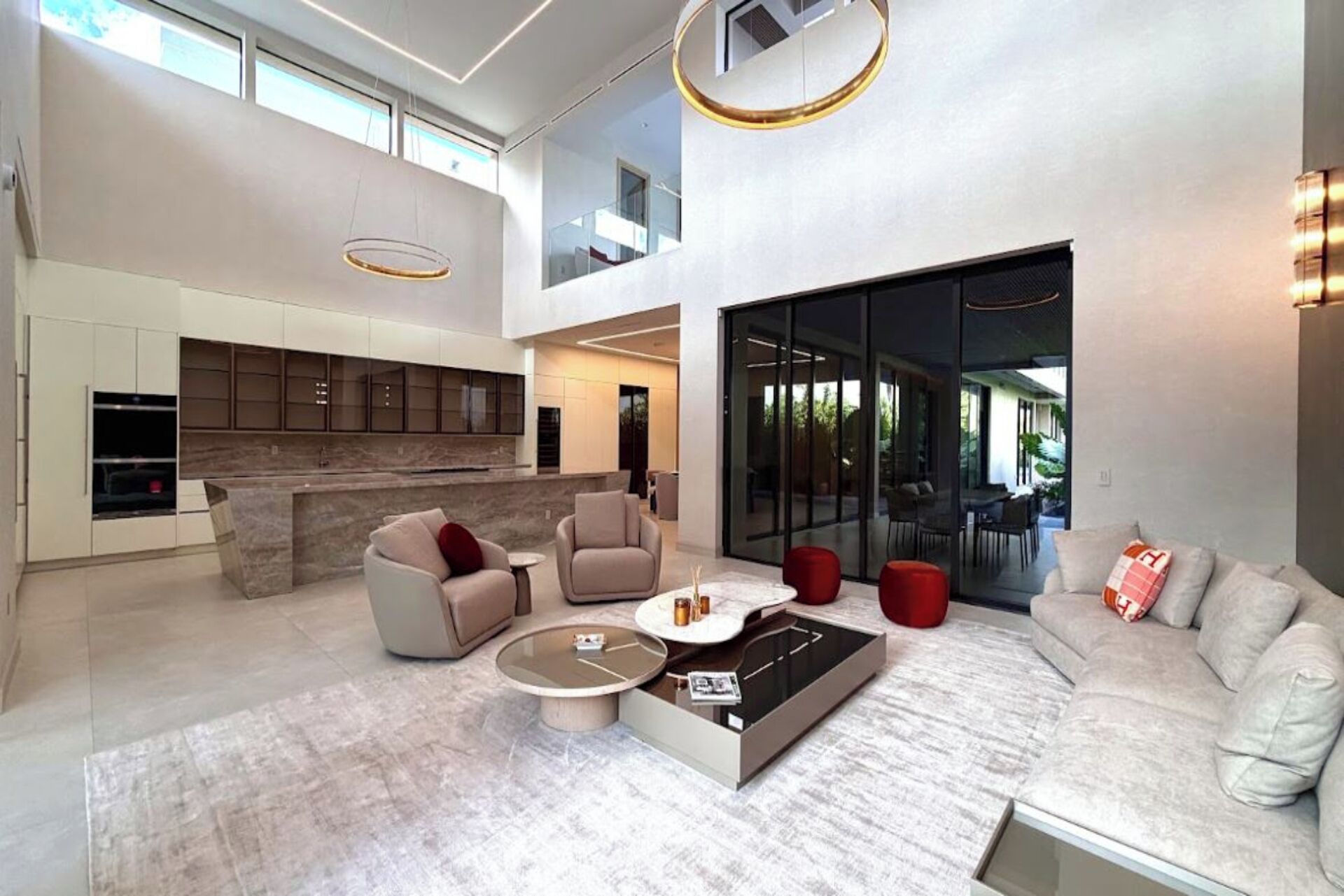 A modern living room with a sofa, armchairs, a coffee table, and a kitchen area with cabinets and a countertop.