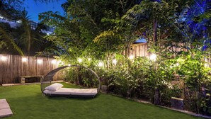 Un jardin bien entretenu, avec une pelouse verdoyante, une clôture en bois et un fauteuil suspendu.