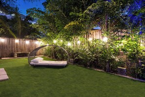 A well-maintained garden with a grassy lawn, a wooden fence, and a hanging chair.