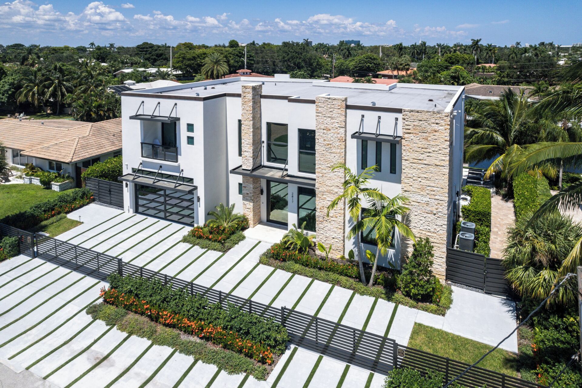 A modern two-story house with a flat roof, large windows, and a stone facade.