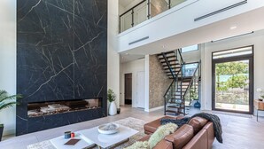 A modern living room with a fireplace, a staircase, and a view of the outdoors. - Brielle (Fort Lauderdale)