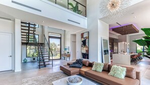 A spacious living area with a brown leather sofa, a coffee table, and a staircase leading to an upper level. - Brielle (Fort Lauderdale)