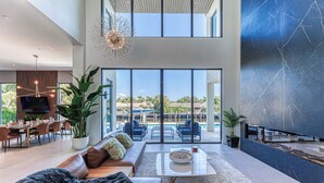 A spacious living area with a large sofa, a coffee table, and a TV. There is a balcony with a pool view. - Brielle (Fort Lauderdale)