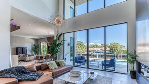 A spacious living area with a large window, a modern chandelier, and a dining area. - Brielle (Fort Lauderdale)