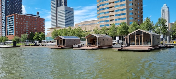 Floating houses with outdoor seating and a water body in the foreground.