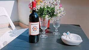 A bottle of BRIANTE CHIANTI CLASSICO wine, two wine glasses, a white bowl with a bow, and a potted plant with flowers on a table with a view of mountains. - Cozy 2-bedroom apartment in enchanting Malgrate with AC (Malgrate)