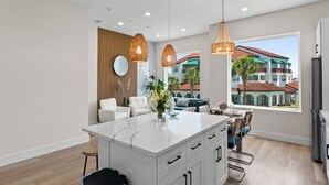 Una cucina moderna con isola centrale, illuminazione a sospensione e vista su una zona residenziale.