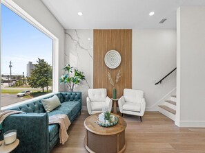 Ein modernes Wohnzimmer mit einer Couch, Sesseln, einem Couchtisch und Blick ins Freie.