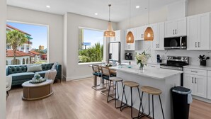 Una cocina moderna con armarios blancos, una isla central y lámparas colgantes.