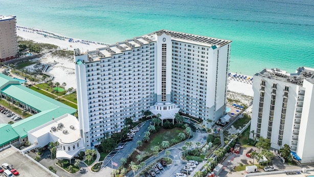 A high-rise hotel with a central courtyard, adjacent to a beach with a clear view of the ocean. - Pelican Beach #2004 | Gulf Front in Destin + Amenities (Destin)