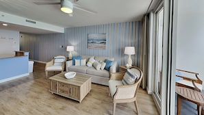 A modern living room with a ceiling fan, a sofa set, a coffee table, and a view through large windows. - Pelican Beach #2004 | Gulf Front in Destin + Amenities (Destin)