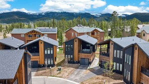 Un complexe hôtelier moderne doté de plusieurs chalets en bois, d’une route principale et d’un paysage montagneux en arrière-plan.