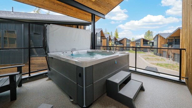 Un bain à remous sous un toit en bois, avec vue sur d’autres bâtiments.