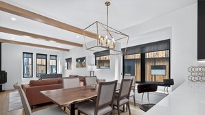 Un espace repas moderne avec une table en bois, des chaises et un luminaire suspendu aux formes géométriques.