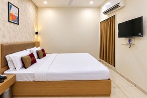 A hotel room with a bed, a nightstand, a TV, and an air conditioning unit. - Aceotel Select Akshar Imperial Morbi (Morbi)
