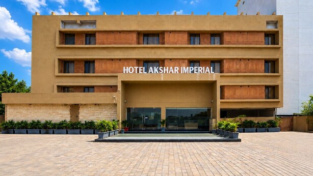 A multi-story hotel with a flat facade, balconies, and a clear sky. -  Hotel Akshar Imperial Morbi (Morbi)