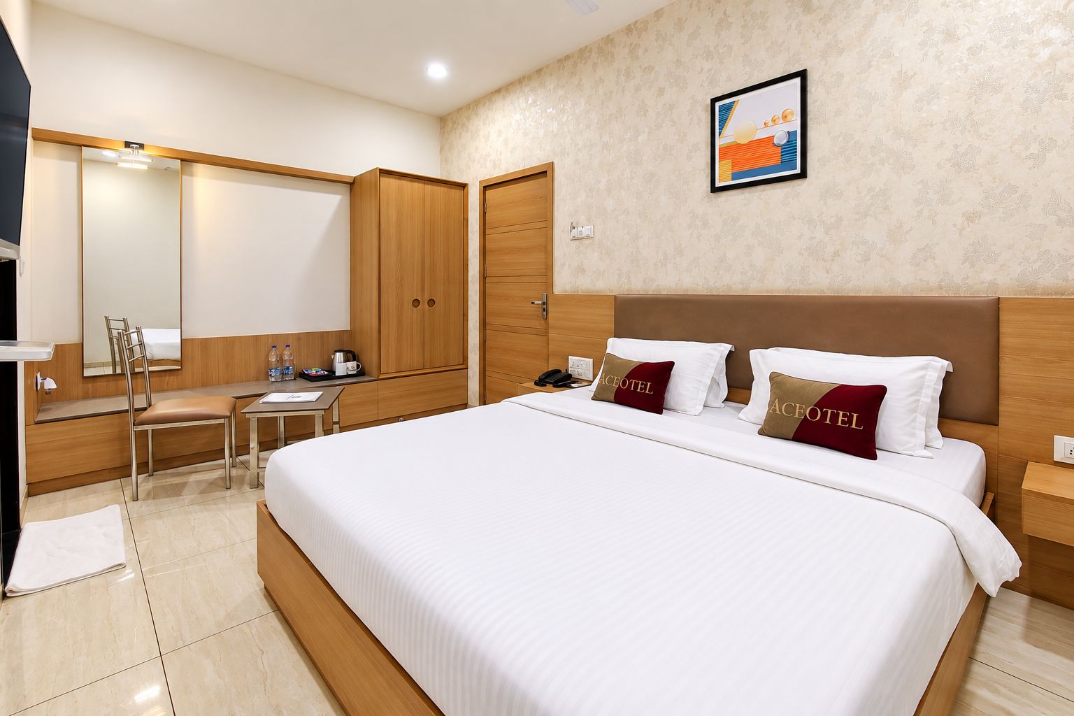A hotel room with a large bed, a desk, a chair, a wardrobe, and a mirror.