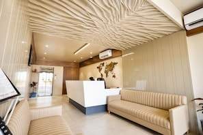 A modern reception area with a world map, a reception desk, a sofa, and a potted plant. -  Hotel Akshar Imperial Morbi (Morbi)