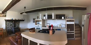 Eine moderne Küche mit Kochinsel, integrierten Geräten und einem Kamin aus Stein.