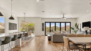 A spacious living area with a large sofa, dining table, and bar seating. - Golf Course Views: Pool + Golf Course Views (Washington)