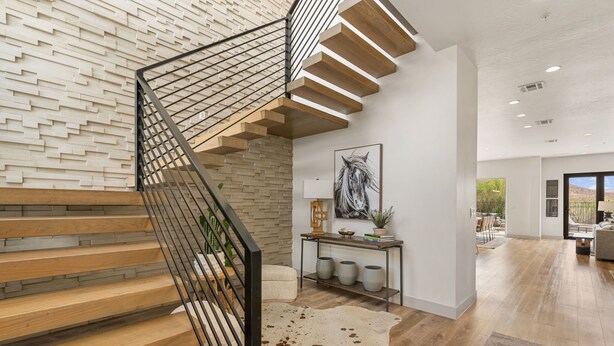 A modern staircase with wooden steps and metal railings, a white wall with a geometric pattern, a mounted artwork, and a view into an adjacent room. - Golf Course Views: Pool + Golf Course Views (Washington)