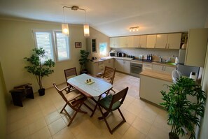 A compact kitchen with a dining table, chairs, and a microwave. - Beautiful 2-3 bed Apt, 360 sea/mountain views in spacious gardens. Pet friendly (Vranovici)