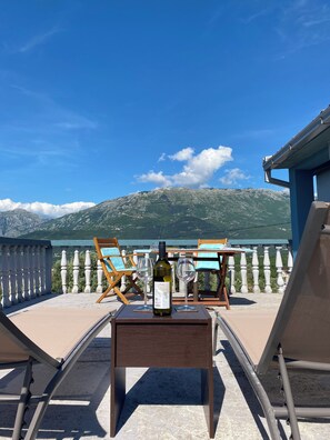 A balcony with two lounge chairs, a table, a bottle of wine, and glasses. - Beautiful 2-3 bed Apt, 360 sea/mountain views in spacious gardens. Pet friendly (Vranovici)