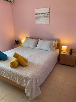 A neatly made bed with rolled towels, a bedside lamp, and a small table with a plant and a lamp. - Beautiful 2-3 bed Apt, 360 sea/mountain views in spacious gardens. Pet friendly (Vranovici)