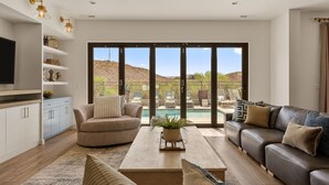 A modern living room with a sofa, coffee table, and TV, with a pool view. - St. George Oasis: Private Pool + Cold Plunge! (Washington)