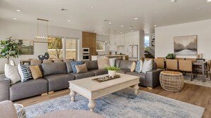 A modern living room with a grey sofa, a wooden coffee table, and a dining area with a table and chairs. - St. George Oasis: Private Pool + Cold Plunge! (Washington)