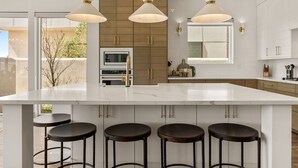 A modern kitchen with a large island, pendant lights, and bar stools. - St. George Oasis: Private Pool + Cold Plunge! (Washington)