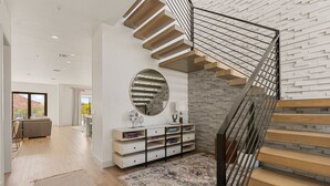 A modern interior with a staircase, a round mirror, a console table, and a view of the outdoors. - St. George Oasis: Private Pool + Cold Plunge! (Washington)