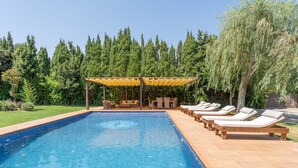 Une piscine avec des chaises longues et un espace de repos abrité.