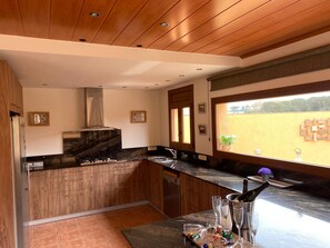 Une cuisine moderne avec des meubles en bois, une hotte en acier inoxydable et une grande fenêtre donnant sur un champ.