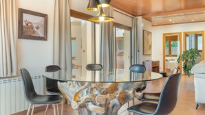 Un espace repas comprenant une table à plateau en verre, des chaises noires, un plafond en bois et un grand miroir.