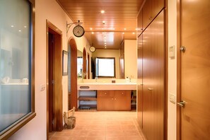 A hallway with wooden doors, a sink, and a clock. - Villa in Llofriu with Pool (Palafrugell)