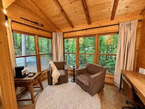 A wooden cabin interior with large windows, a fireplace, and a cozy seating area. - 2BR w/Hot Tub*Fire Pit*Games*Privacy*Walk to Pool! (Sevierville)