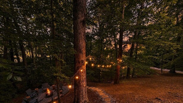 A forested area with a stone pathway leading to a seating area with chairs and a fire pit. - 2BR w/Hot Tub*Fire Pit*Games*Privacy*Walk to Pool! (Sevierville)