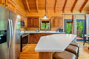 Eine Küche mit Holzausstattung, einem Edelstahlkühlschrank und einer großen Kochinsel mit Barhocker.