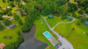 Ein Luftbild eines Anwesens mit Schwimmbad, mehreren Gebäuden und einem See.