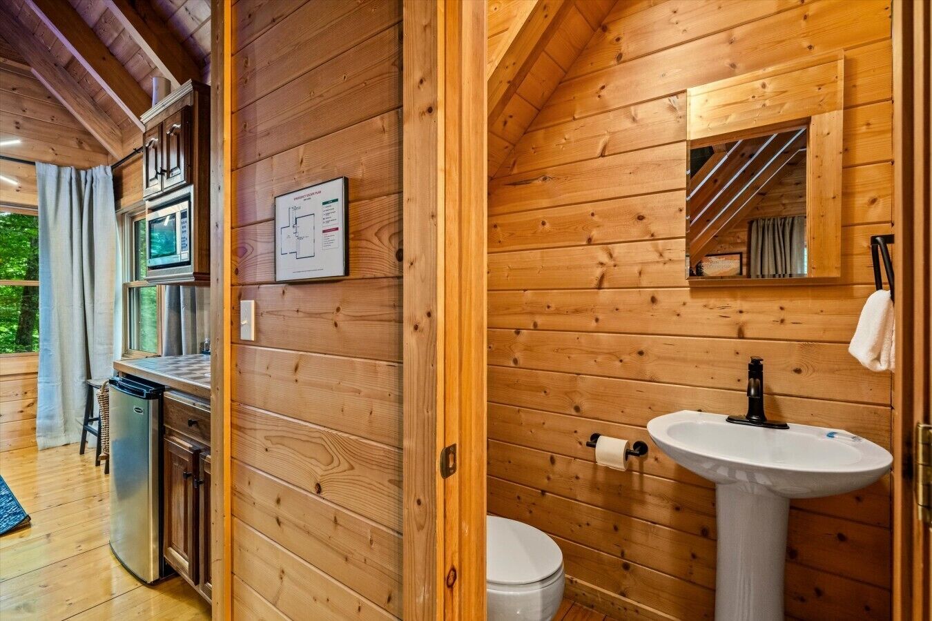 A wooden cabin interior with a kitchenette, a sink, and a toilet.