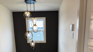 Una escalera con barandilla de madera, pared negra y ventana con persianas.
