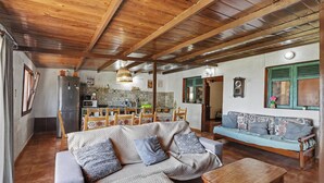 A cozy living room with a wooden ceiling, a sofa, a coffee table, and a dining area with chairs and a table. - Finca El Lomo with Mountain Views, Private Pool and Wi-Fi (Saucillo)