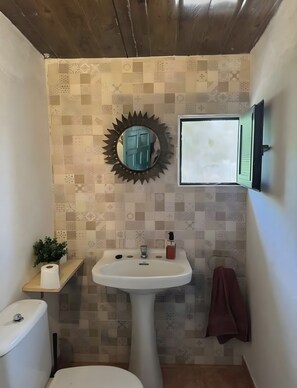 A bathroom with a sink, mirror, toilet, and patterned wall tiles. - Finca El Lomo with Mountain Views, Private Pool and Wi-Fi (Saucillo)