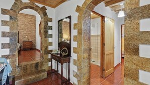 A room with stone arches, a wooden ceiling, a mirror, a wooden dresser, and a tiled floor. - Finca El Lomo with Mountain Views, Private Pool and Wi-Fi (Saucillo)