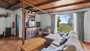 A living room with a wooden ceiling, a sofa, a TV, a cabinet, and a view of the outdoors. - Finca El Lomo with Mountain Views, Private Pool and Wi-Fi (Saucillo)